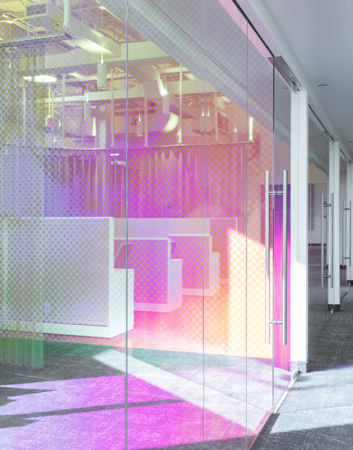Bright, open-concept office interior featuring a modern architectural staircase and colorful, translucent purple and pink accent panels.