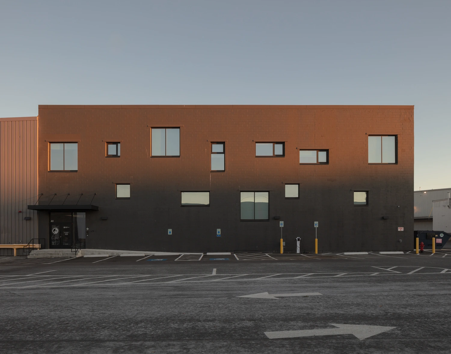 Exterior view of a modern multi-story commercial building with rectangular windows under an overcast sky.