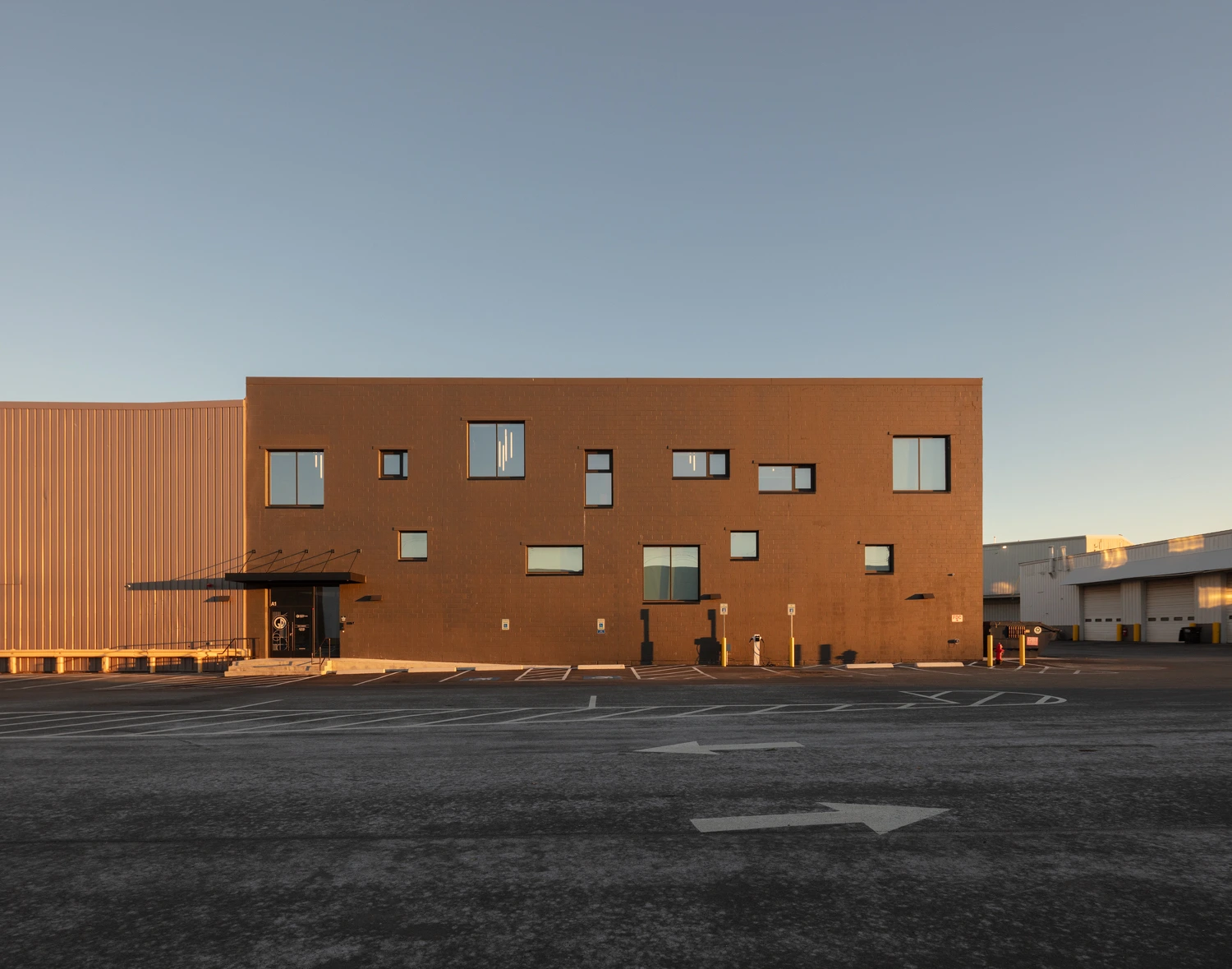 Daytime exterior view of a modern multi-story office building with warm brown siding and randomly arranged square windows.