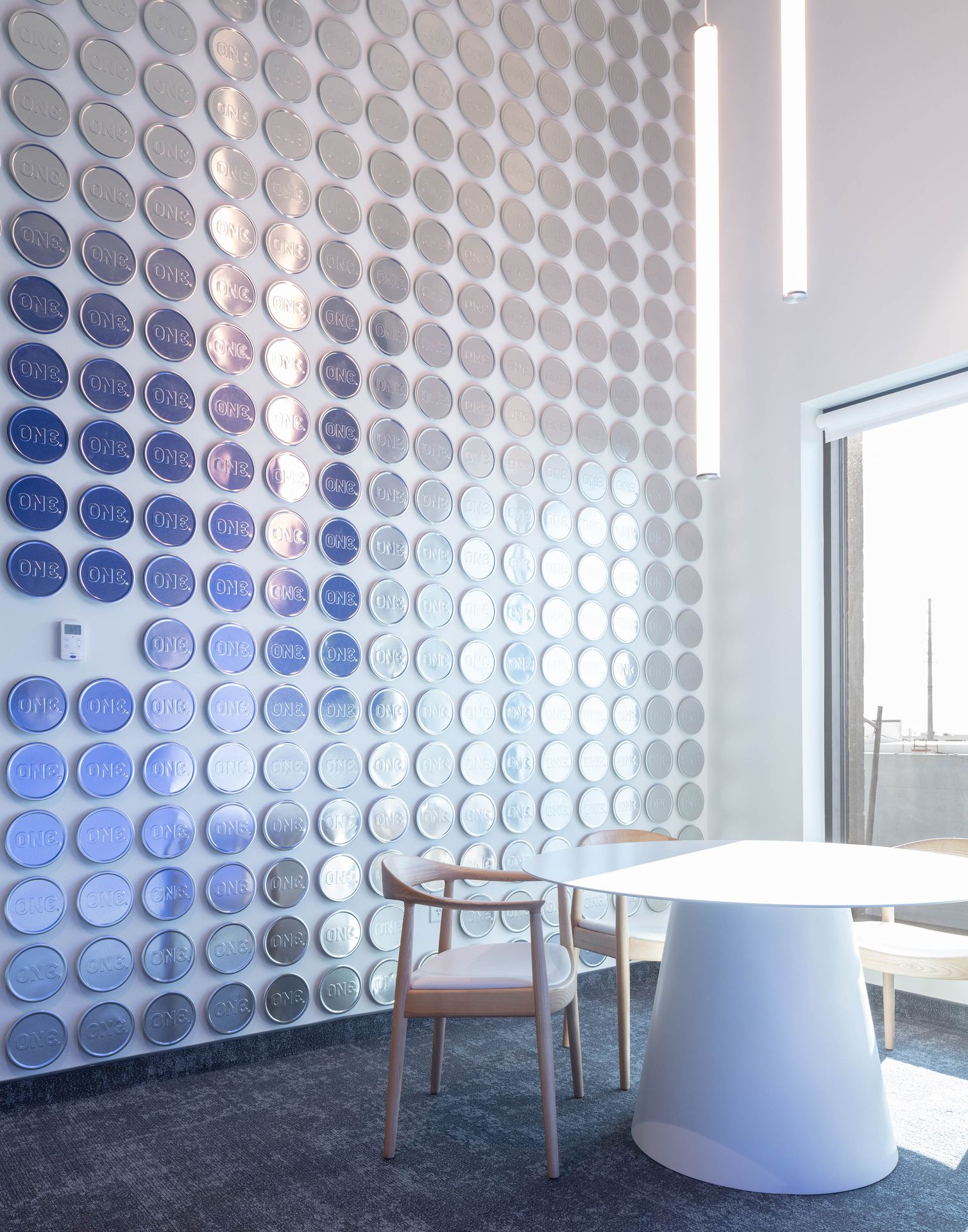 A modern office meeting area featuring a prominent accent wall covered in a large-scale artistic mural composed of blue and white circular patterns.