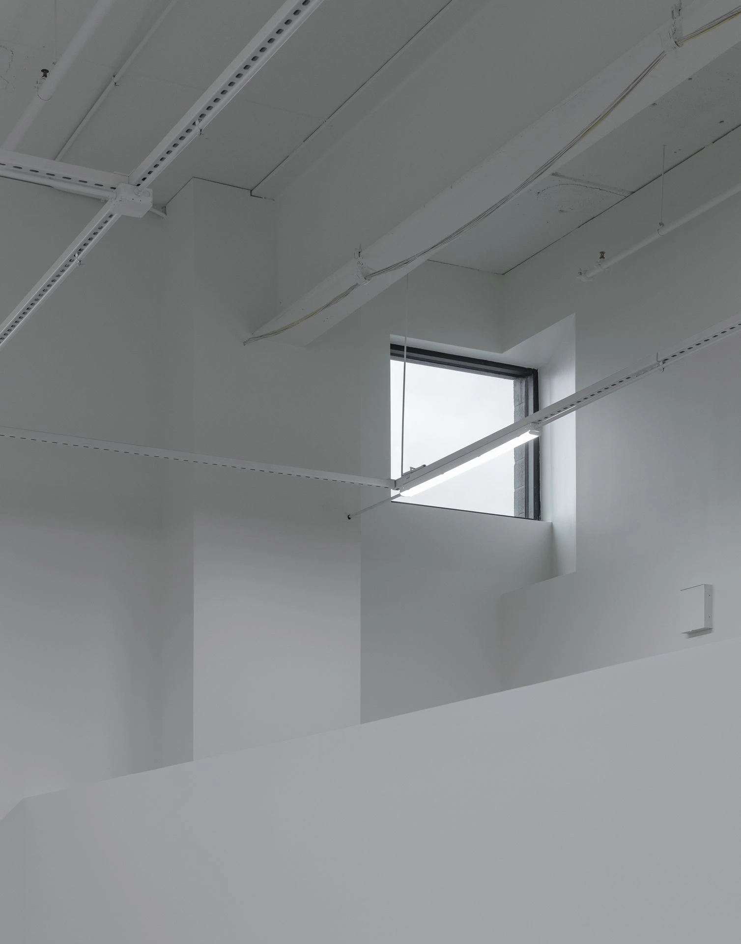 Architectural perspective looking up at an interior white ceiling with an angled skylight window casting natural light down the walls.