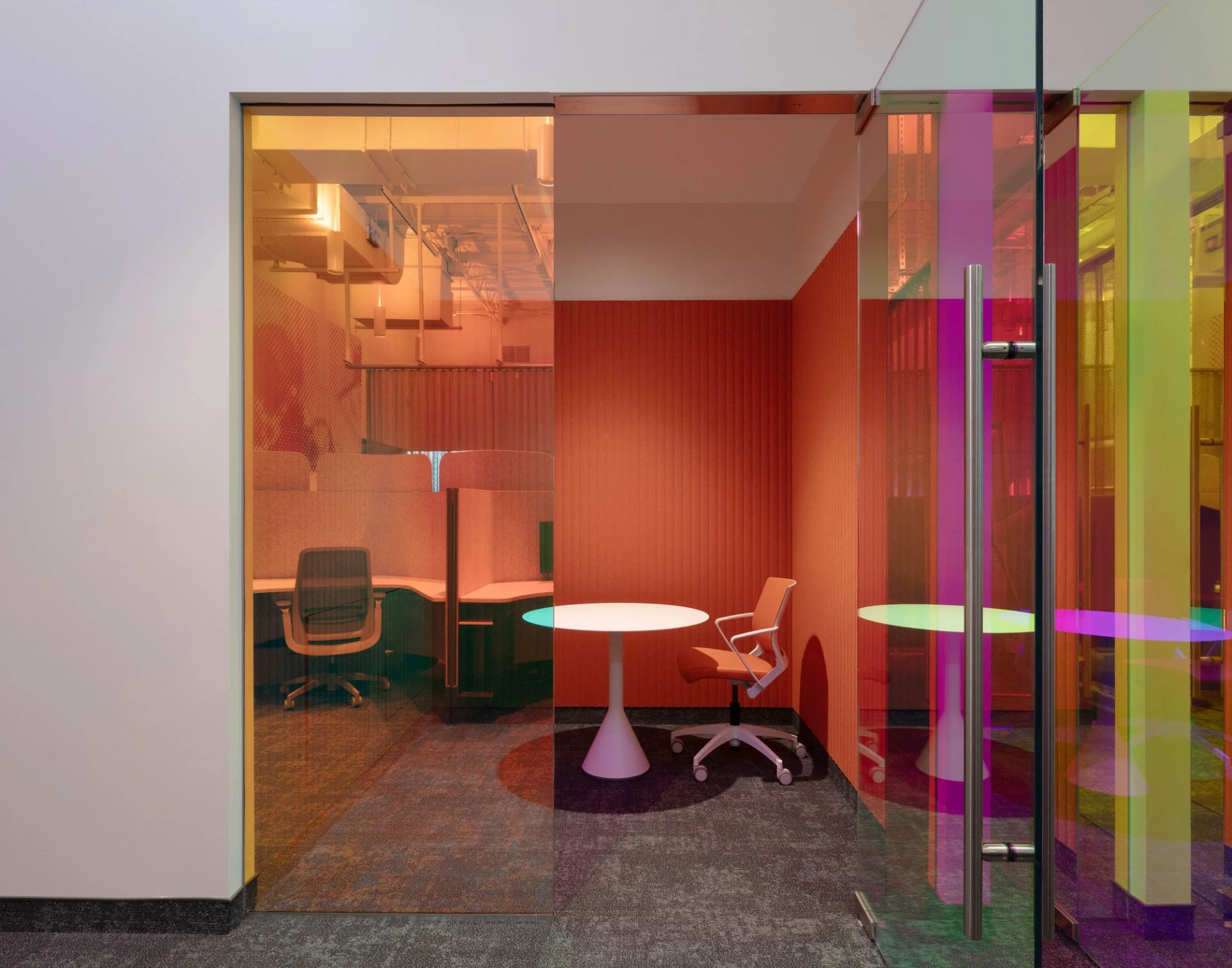 Interior shot of a contemporary office lobby featuring colorful, translucent glass partitions in vibrant shades of pink and orange.