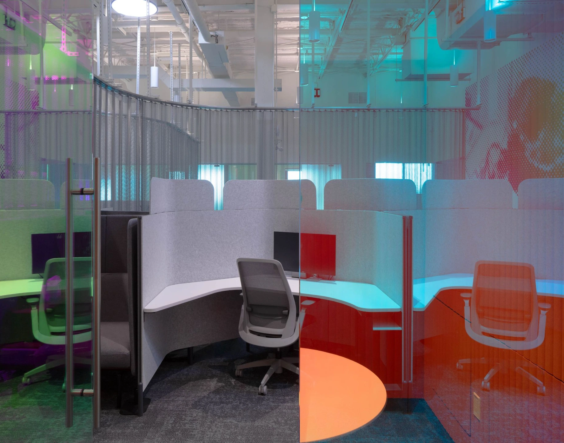 A modern open-concept office workspace showing a built-in orange counter area and structured desk partitions.