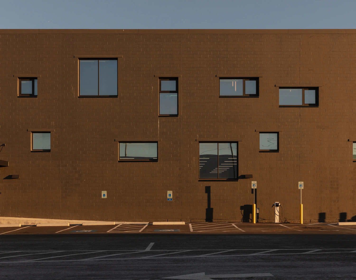 Close-up architectural detail of an exterior building corner showing a patterned array of square windows against dark paneling at night.