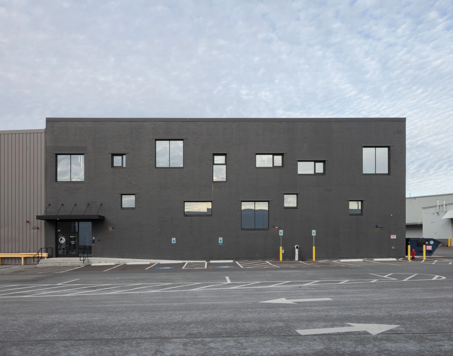 Black and white architectural photograph of a modern commercial building exterior featuring multi-toned rectangular siding and geometric windows.