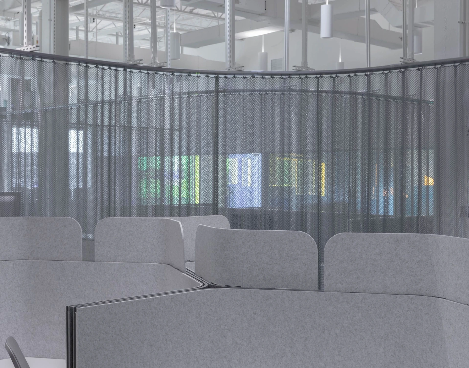 Indoor view of a wide, open industrial workspace with concrete floors, white walls, and high ceilings.