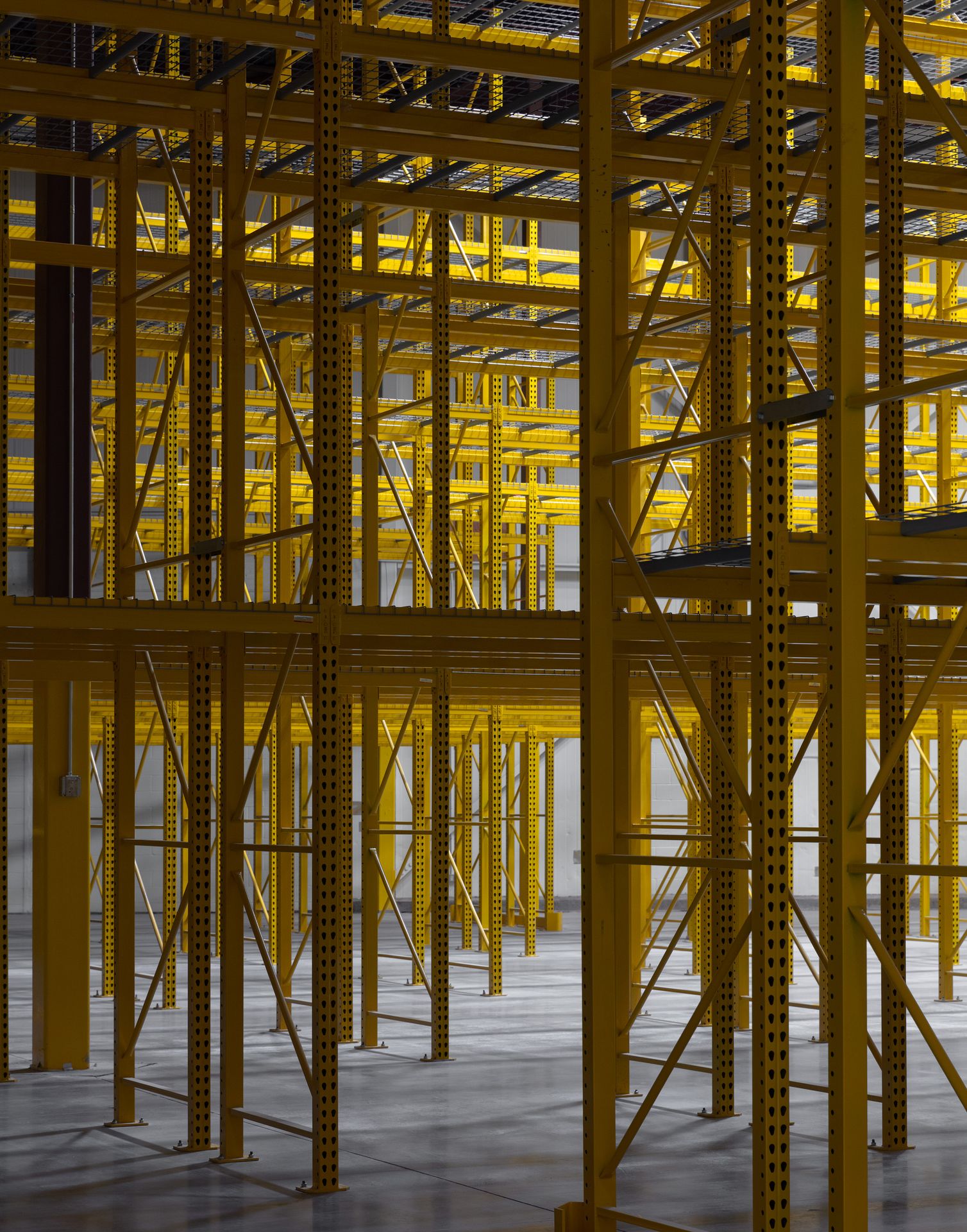 Perspective shot looking up at the towering steel frame of yellow warehouse shelving units.